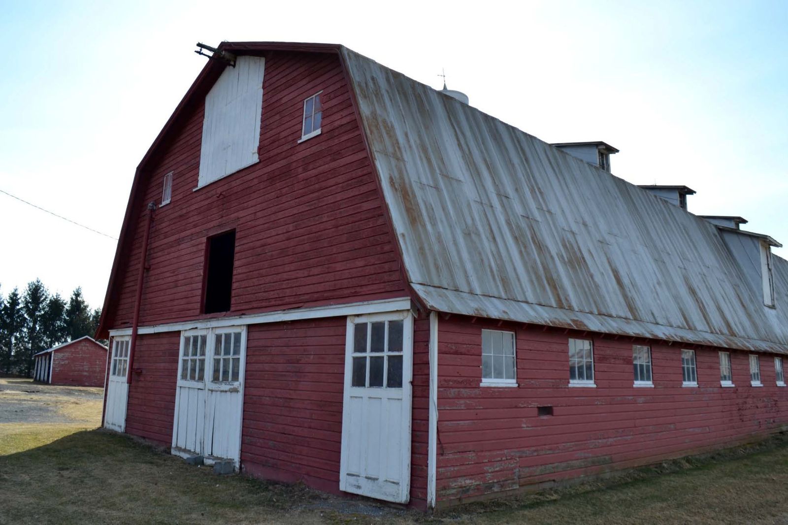 Front façade with gambrel roof and dormers, facing southwest.